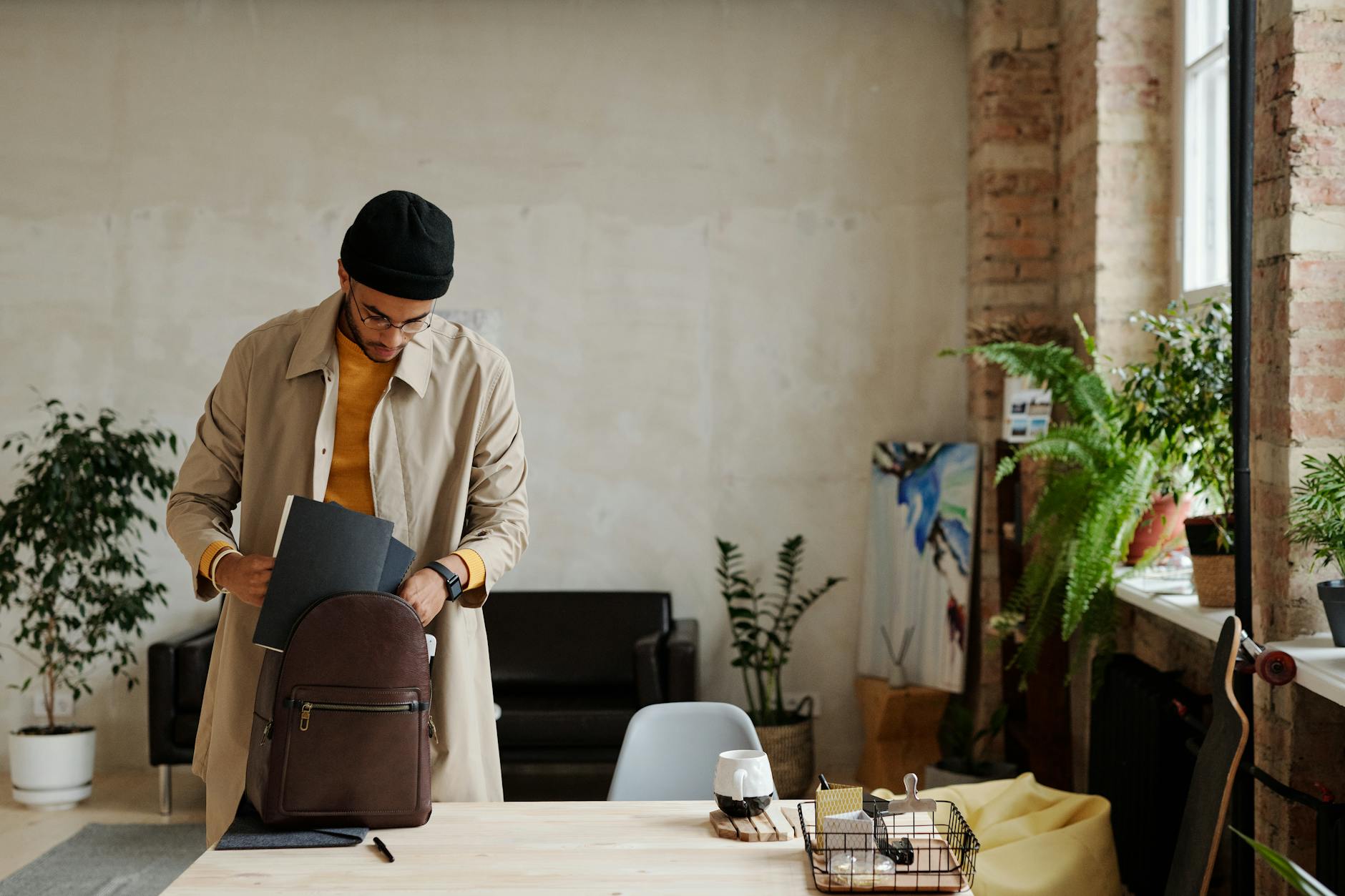 Mężczyzna pakuje modny plecak w nowoczesnym, jasnym lofcie z roślinami