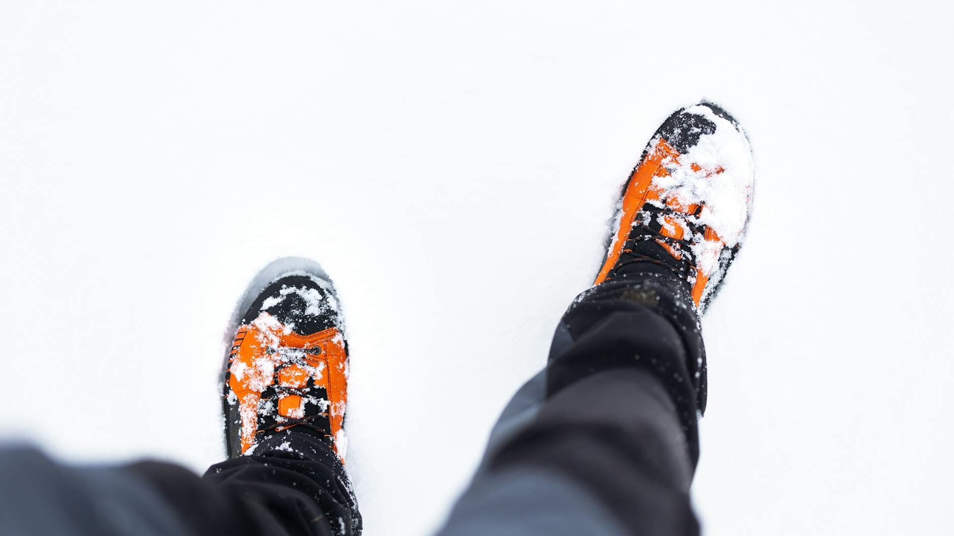 Pomarańczowe buty zimowe z góry, pokryte śniegiem na spacerze