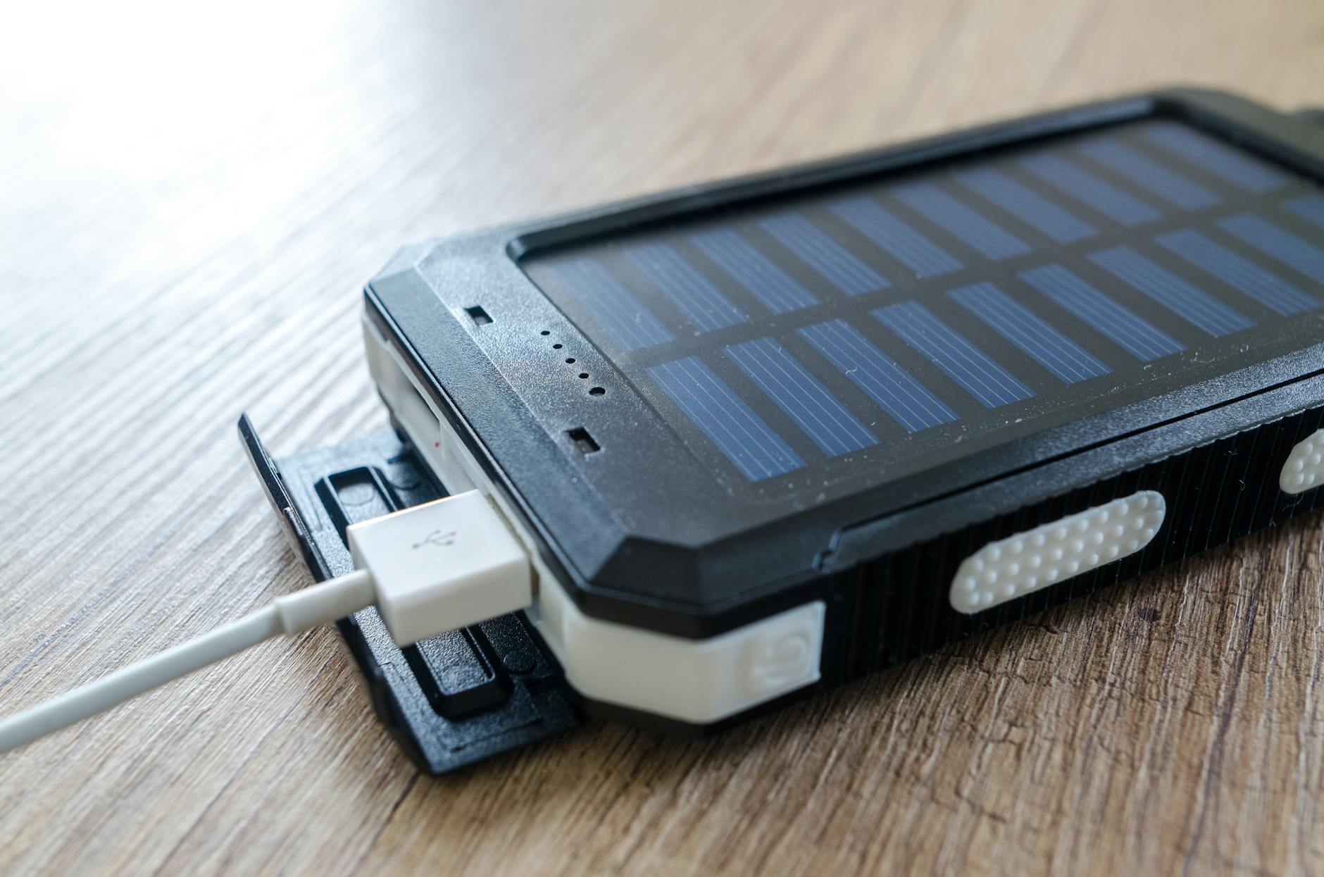 Zbliżenie na solarny powerbank z portem USB na drewnianym blacie