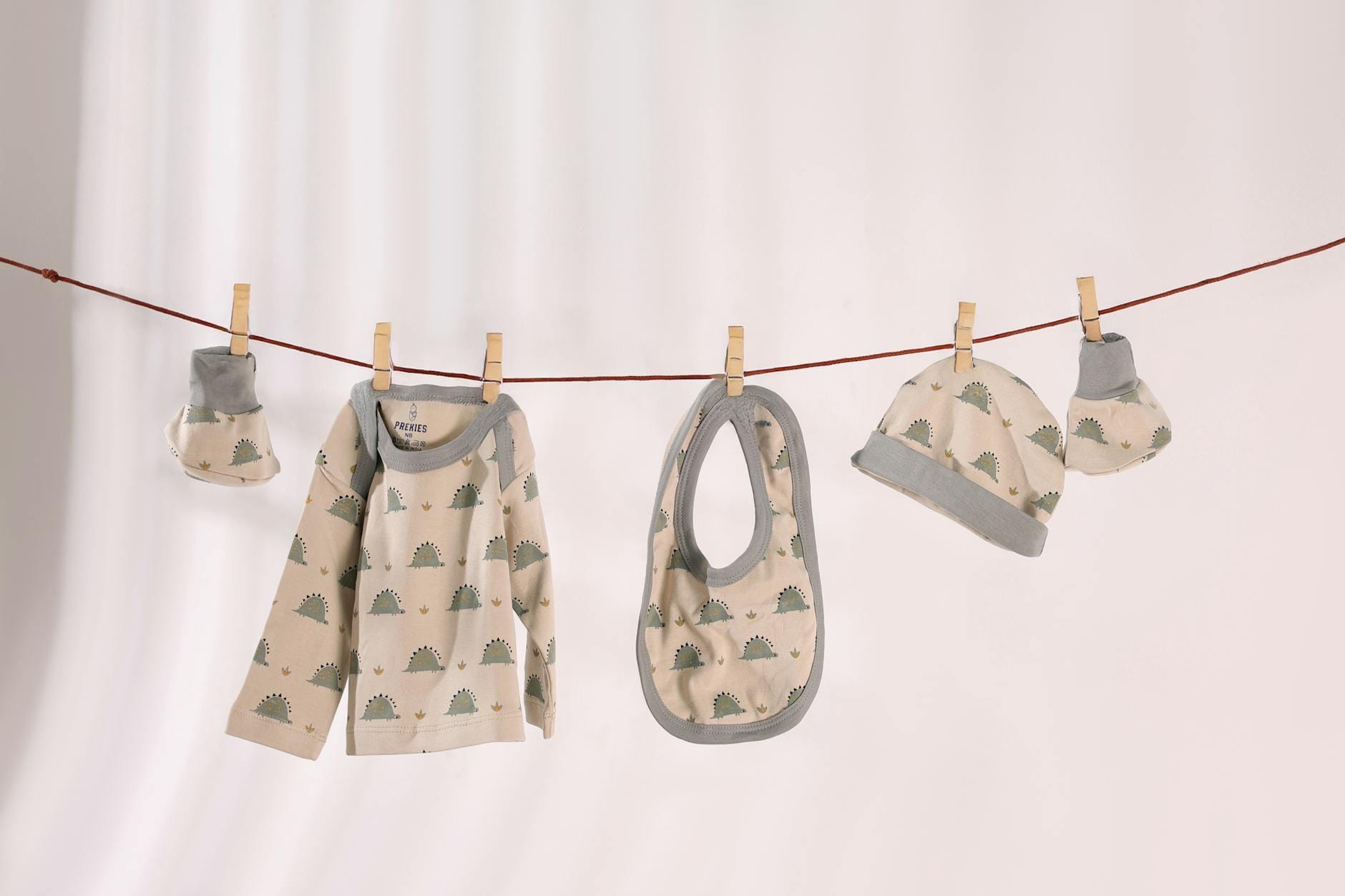 Zestaw ubranek niemowlęcych w pastelowe wzory zawieszony na sznurku