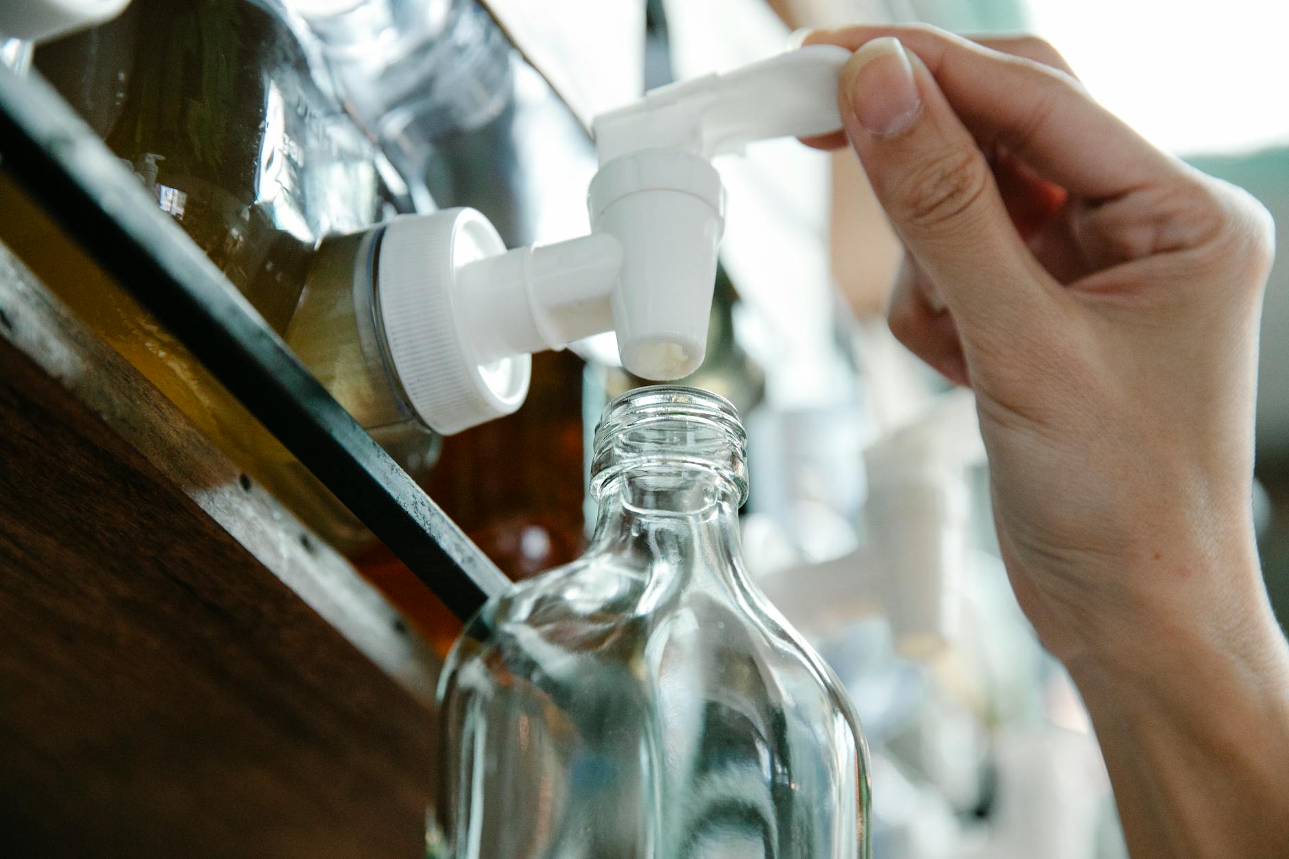 Nalewanie wody do szklanej butelki z dozownika w sklepie zero waste