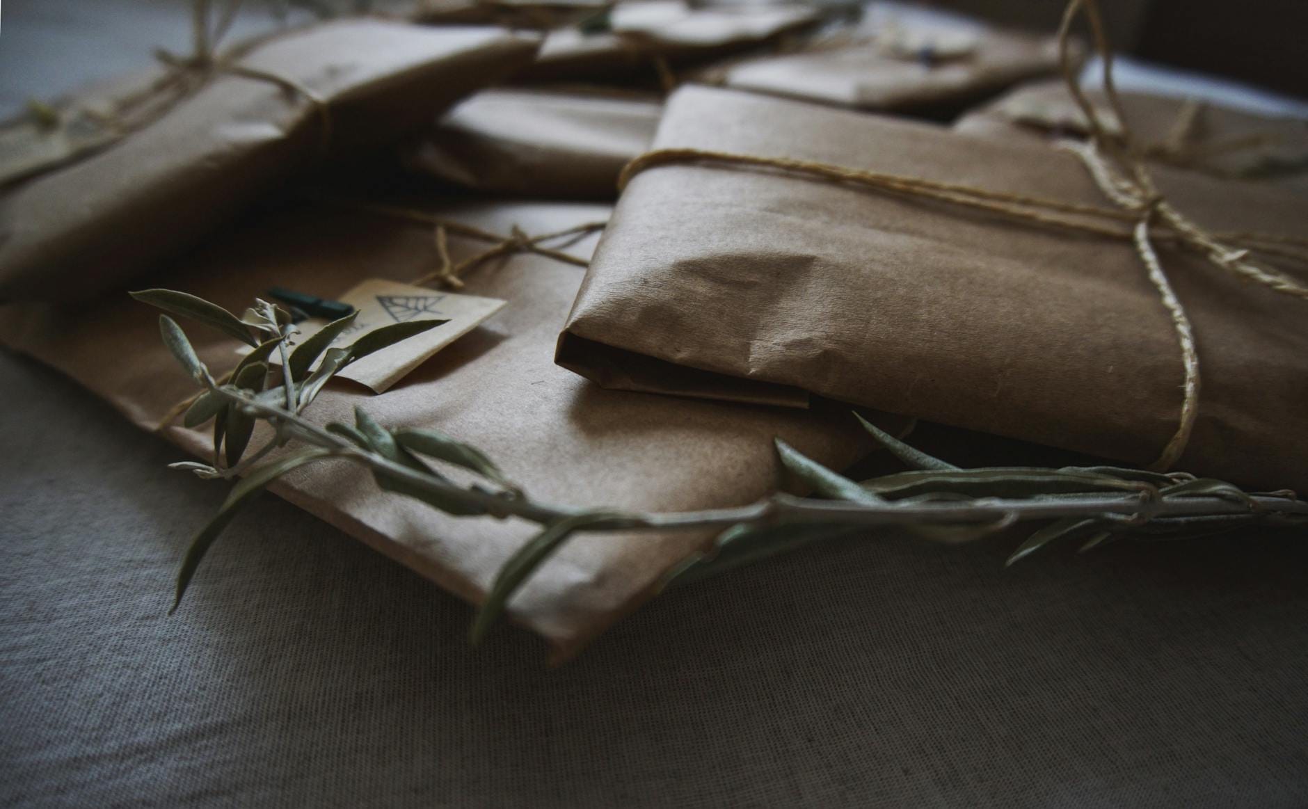 Prezenty zero waste zapakowane w brązowy papier z jutowym sznurkiem i liśćmi