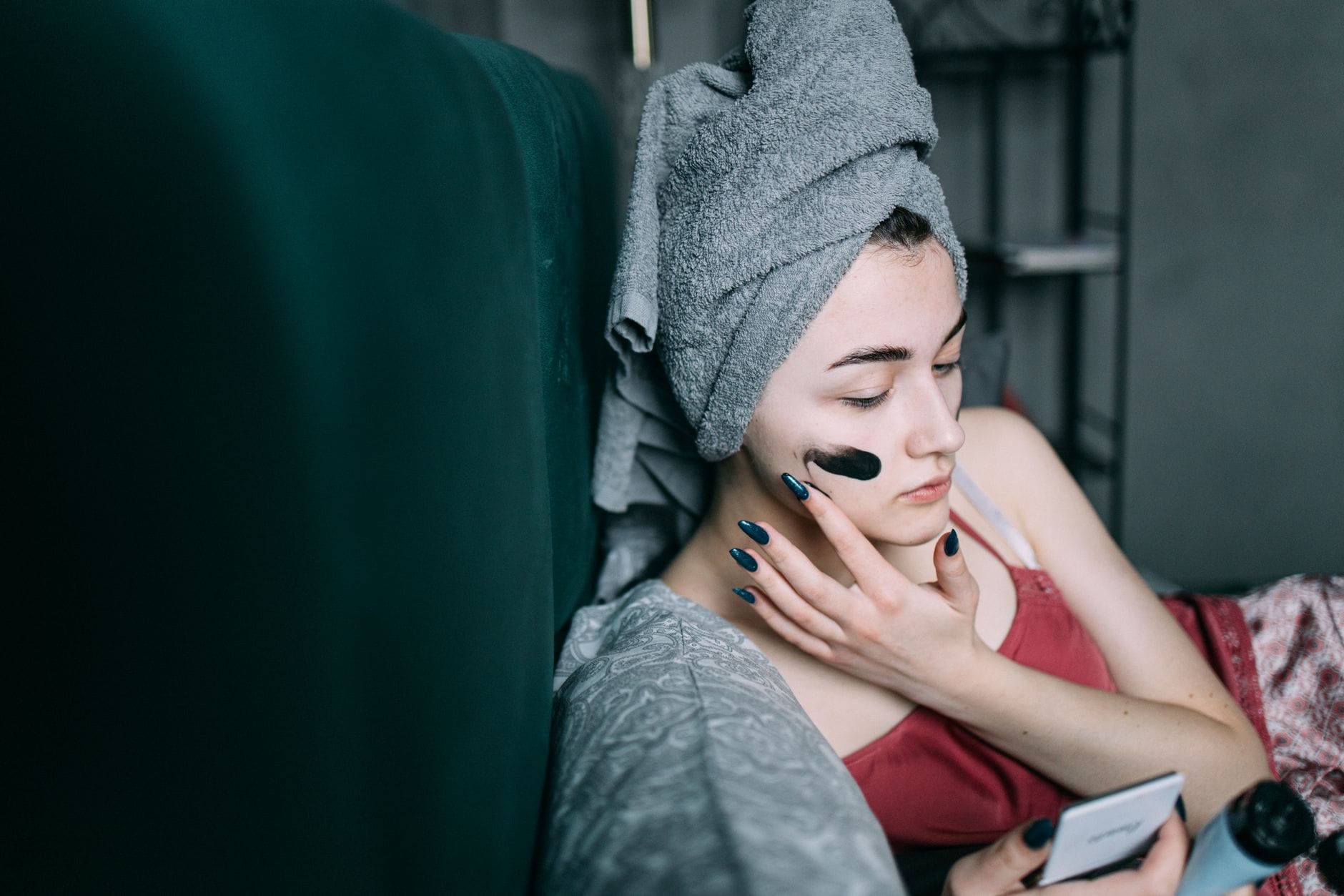 Kobieta w ręczniku na głowie nakłada maseczkę podczas domowej pielęgnacji